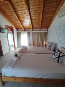 two beds in a room with wooden ceilings at Chloe attic in Agia Effimia