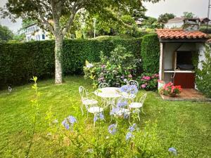 een tuin met een tafel en stoelen in het gras bij Argizaria in Ciboure