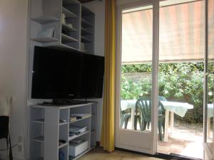 a living room with a television and a sliding glass door at domino in Saint-Georges-dʼOléron