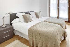 1 Schlafzimmer mit 2 Betten mit weißer Bettwäsche und einer Lampe in der Unterkunft Cap 1500 by FeelFree Rentals in Baqueira-Beret