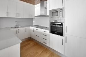 cocina blanca con armarios blancos y microondas en Cap 1500 by FeelFree Rentals, en Baqueira Beret