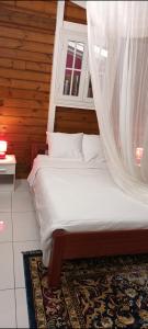 a bedroom with a bed with a mosquito net at Anara-Rose ensoleillée in Bouillante