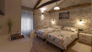 a bedroom with two beds and a stone wall at Villa Casa Pintori in Buzet +34 photos