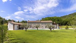a large stone house with trees in a field at Villa Casa Pintori in Buzet