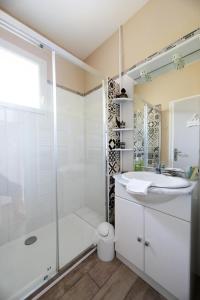 a white bathroom with a shower and a sink at Appartement les hirondelles in Saint-Pair-sur-Mer