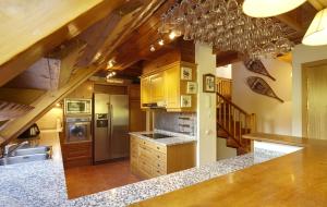 una cocina con armarios de madera y electrodomésticos de acero inoxidable en Era Garona by FeelFree Rentals, en Vielha
