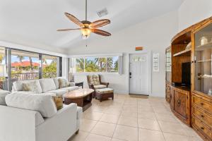 Una sala de estar con muebles blancos y un ventilador de techo. en Canal-side Charisma, en Key Colony Beach