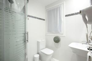 Un baño blanco con inodoro y lavabo. en Pensión San Jerónimo, en San Sebastián