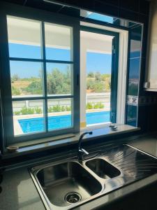 a kitchen with a sink and a window above a kitchen counter at Vivenda Soares in Estômbar