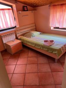 a small bedroom with a bed and two windows at Apartma Mimi in Dekani