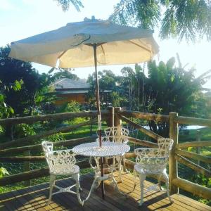 a table and chairs with an umbrella on a deck at Casa dentro da floresta in Campos do Jordão