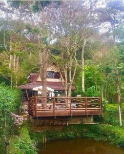 a house on a bridge over a body of water at Casa dentro da floresta in Campos do Jordão