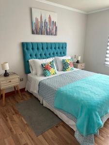 a bedroom with a large bed with a blue headboard at Condominio Mar Egeo Iquique in Iquique +20 photos