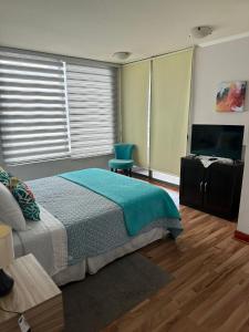 a bedroom with a bed and a flat screen tv at Condominio Mar Egeo Iquique in Iquique