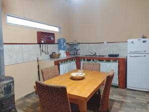 a kitchen with a wooden table with chairs and a refrigerator at Cabaña Los Cardones in Campanas