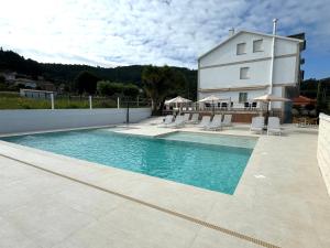 a swimming pool in front of a white building at Naturmar in Raxó