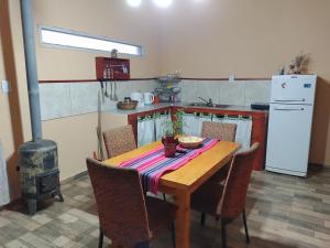 a kitchen with a wooden table with chairs and a stove at Cabaña Los Cardones in Campanas