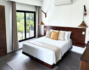 a bedroom with a large bed and a large window at Villa Tucanes in Tulum
