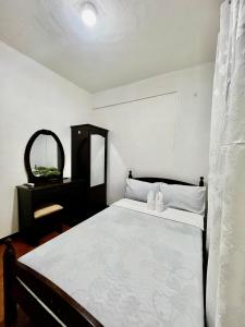 a bedroom with a bed with a dresser and a mirror at 2BR Kelsey Haven With Balcony in Davao City