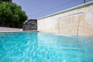 a swimming pool in front of a stone wall at Casa Rosado Rincon Rayo Suite Mountain View Pool in Rincon