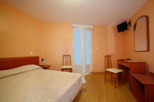 a bedroom with a bed and a desk and a television at Hotel le Dauphin in Ajaccio