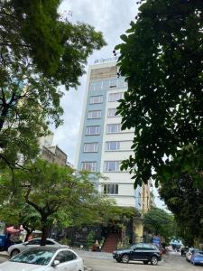 a tall white building with cars parked in front of it at Song Lộc Hạ Long Hotel in Ha Long +7 photos