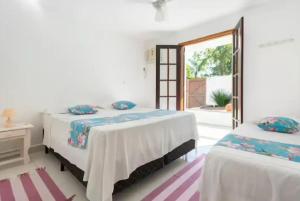 deux lits dans une chambre blanche avec une fenêtre dans l'établissement Suíte Praia em Guarujá, à Guarujá