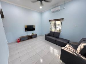 a living room with a couch and a tv at Afdal homestay in Pantai Cenang
