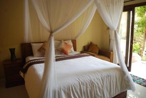 a bedroom with a white bed with a canopy at Dalum Homestay in Amed