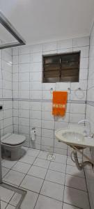 Baño de azulejos blancos con aseo y lavamanos en Iguaçu House, en Foz do Iguaçu 12 fotos más