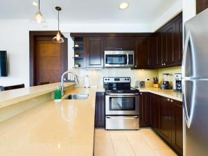 Una cocina con gabinetes de madera y electrodomésticos de acero inoxidable. en 360 Splendor 404-Ocean View Condo- With Breakfast, en Playa Flamingo