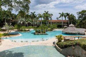 a pool at a resort with palm trees at Matapalo 203- 2 Bedroom Condo At Tamarindo in Tamarindo