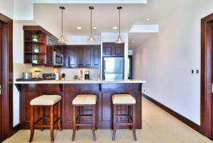 a kitchen with wooden cabinets and a counter with stools at 360 Splendor 305 Ocean View Condo- With Breakfast in Playa Flamingo