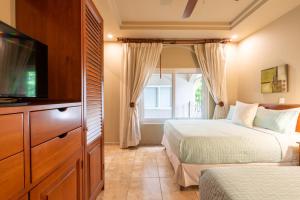 a bedroom with two beds and a flat screen tv at Matapalo 302- 2 Bedroom Condo At Tamarindo in Tamarindo +30 photos