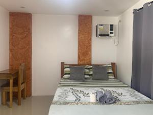 a small bedroom with a bed and a desk at Hidden Garden Pensione in El Nido