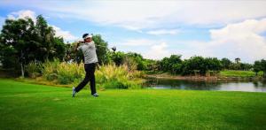 Un uomo che dondola una mazza da golf su un campo di Centro Guest House a Siem Reap