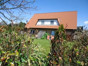 a house with an orange roof and some bushes at Alter Badweg Holiday Apartment 4 in Sankt Peter-Ording