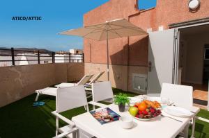 a table and chairs with a bowl of fruit on a balcony at Hotel Apartamento Bajamar in Las Palmas de Gran Canaria