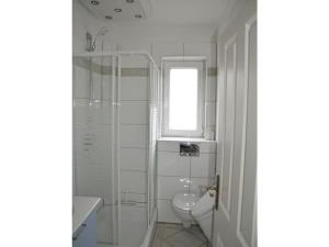 a white bathroom with a toilet and a window at Strandrausch Comfortable holiday residence in Scharbeutz +6 photos