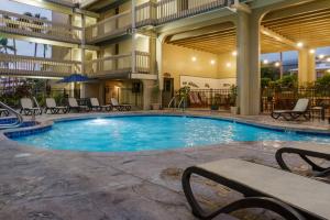 a swimming pool in a hotel with chairs and a table at Ocean-front penthouse, sunsets, whales, surfers! Newly remodeled! in Kailua-Kona