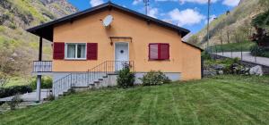 AquinoParadiso in verzasca Motta的一座带红色百叶窗和庭院的房子