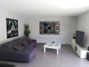 a living room with a purple couch and a tv at Villa piscine chauffée,5ch ,climatisation, bar extérieur in Lacanau