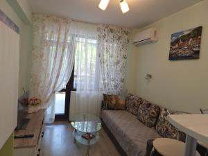 Una sala de estar con un sofá y una ventana. en Green Paradise apartman 105, en Primorsko