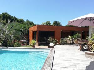 a swimming pool with a deck and a house at Villa piscine chauffée,5ch ,climatisation, bar extérieur in Lacanau