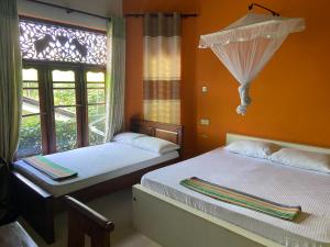 two beds in a room with a window at Bee Nest Bed & Breakfast in Negombo