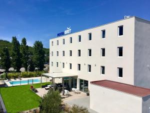 a white building with a pool in front of it at Brit Hotel Martigues Nord in Martigues