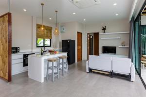 a kitchen with white cabinets and a kitchen island with stools at 2br Seaview pool villa B in Hinkong