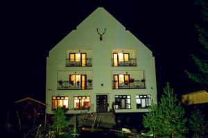 a large white building with windows at night at Pensiunea Fish Valley in Cîmpu lui Neag