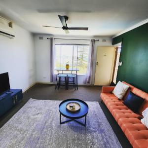 a living room with a couch and a table at Casa Luna Beachside Apartment in Henley Beach South