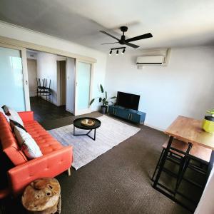 a living room with an orange couch and a table at Casa Luna Beachside Apartment in Henley Beach South
